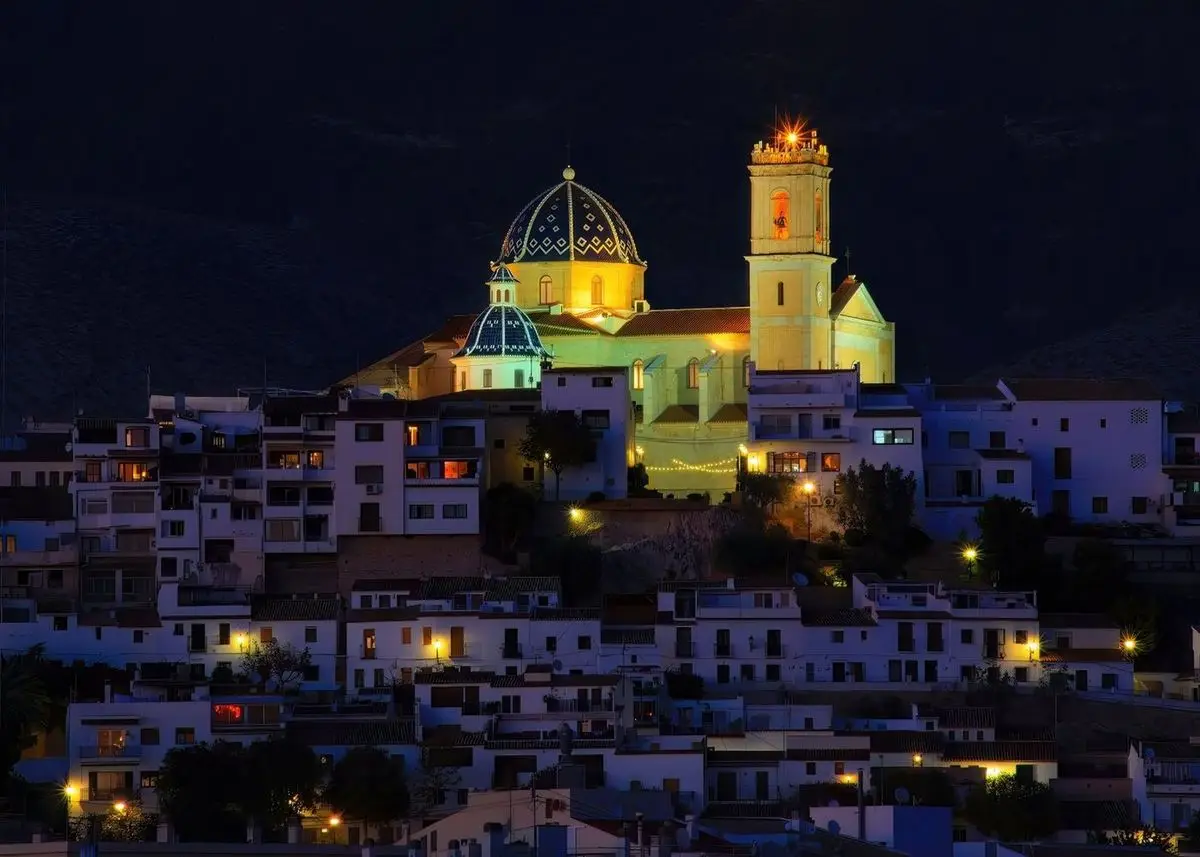 Altea de noche: la colina cubierta de casas blancas y, encima, la parroquia iluminada con su cúpula azul y el campanario