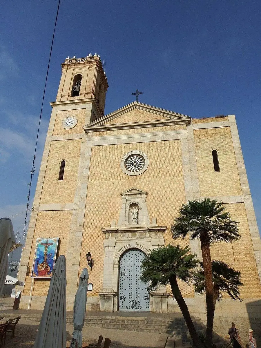 La fachada de la iglesia parroquial: ladrillo con recercados de sillería, rosetón, hornacina sobre la portada y, a la izquierda, el campanario con reloj
