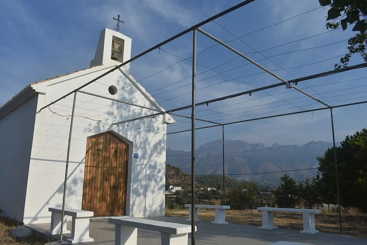 La ermita de Sant Lluís de frente, con la campana en la espadaña y, detrás, la Serra de Bèrnia
