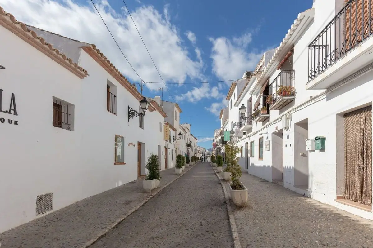La calle Sant Miquel cuesta arriba: empedrado de cantos, casas blancas con balcones de forja y macetones en medio de la calle