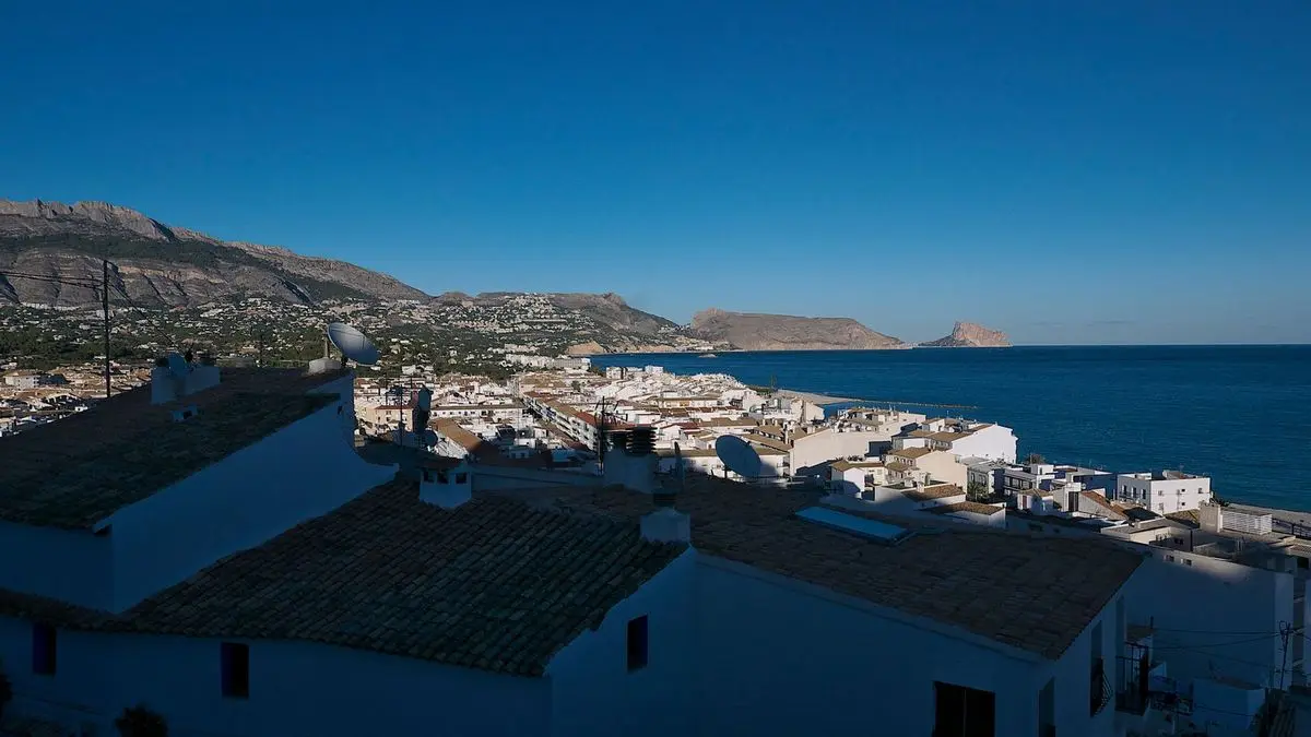 Uitzicht vanaf het uitkijkpunt over de daken van de oude stad naar het lager gelegen deel van het dorp, de baai en aan de horizon enkele rotsachtige kapen