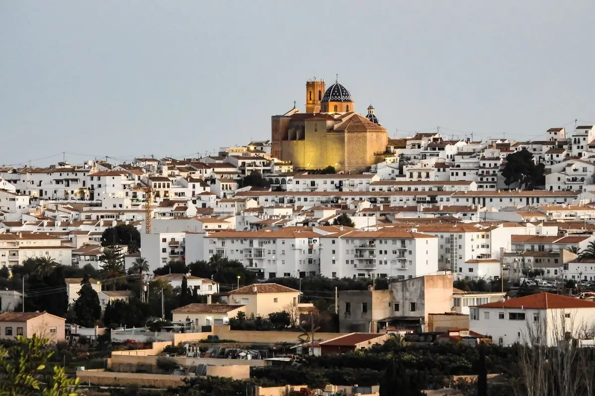 Toda la colina desde lejos, al anochecer: centenares de casas blancas escalonadas y, encima, la iglesia iluminada con su cúpula y su torre